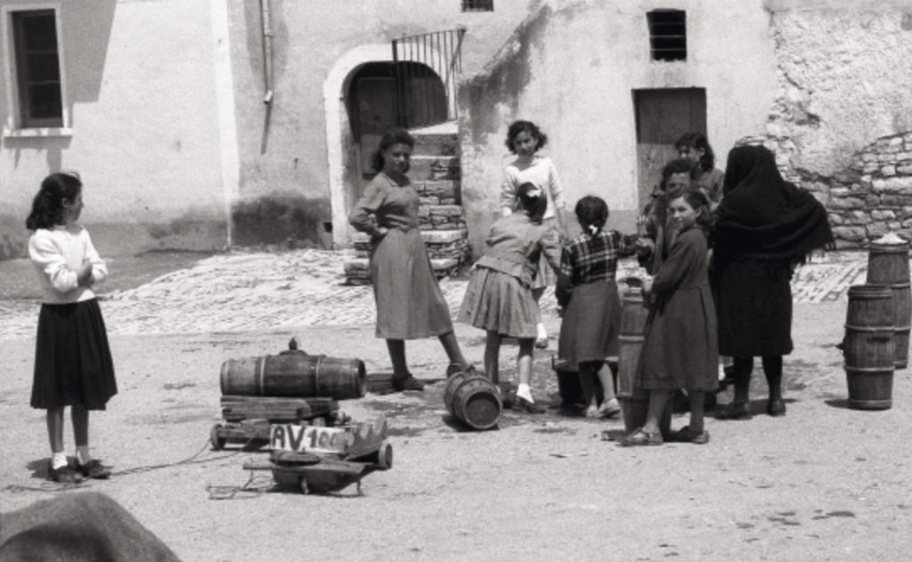 Young women and girls in Lacedonia stand in the street surrounded by thin barrels. Frank Cancian image.