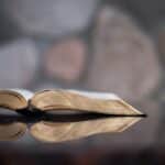 An open book seen from the side with reflection on a table